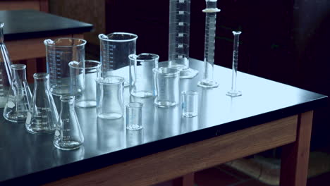 Tilting-up-to-reveal-black-lab-bench-with-a-variety-of-chemical-glassware-in-high-school-chemistry-lab
