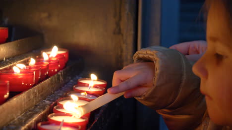 Detail-of-a-beautiful-blonde-little-girl-lighting-candles-carefully-in-a-church-and-then-blowing-them