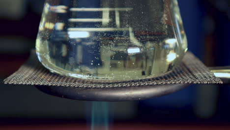 Close-up-of-Erlenmyer-Flask-that-is-being-heated-by-a-bunsen-burner-less-condensation-on-top,-heat-waves-visible-in-flask,-bubbles-beginning-to-form