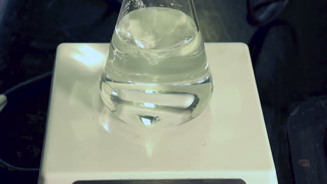 Close-up-of-clear-liquid-in-erlenmeyer-flask-on-a-magnetic-stirrer