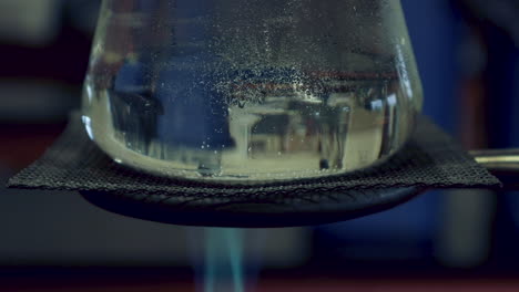 Close-up-of-Erlenmyer-Flask-that-is-being-heated-by-a-bunsen-burner-condensation-on-top,-heat-waves-visible-in-flask