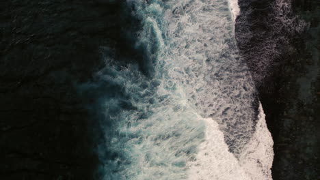 Aerial-birds-eye-view-of-dramatic-dark-moody-ocean-water-with-white-waves-breaking