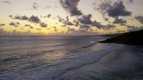 Aerial-pan-left-of-a-beautiful-ocean-sunset-as-waves-break-on-a-beach