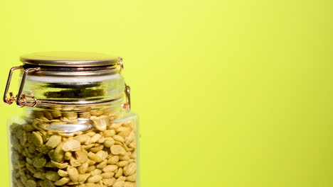 Detail-of-an-airtight-mason-jar-rotating-with-dry-toasted-soybeans-halves-on-a-neon-lilac-background