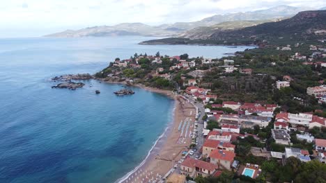 Stoupa-Beach-Town-during-Late-Summer-at-Peloponnese,-Greece---Reversing-Aerial