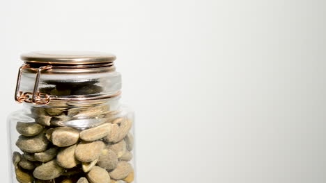 Mason-jar-full-of-toasted-Almond-nuts-rotating-on-white-background-with-room-for-copyspace