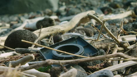 Washed-up-plastic-lies-on-a-beach-amongst-driftwood