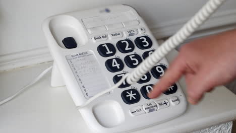 Man-dialling-a-number-on-a-landline-phone