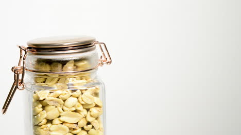A-glass-jar-full-of-peanuts-spinning-on-a-plain-white-background