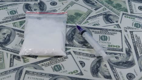 Langsames-Gleiten-über-Drogen-Und-Spritzen,-Die-Auf-Hunderten-Von-US-Dollar-Scheinen-Liegen
