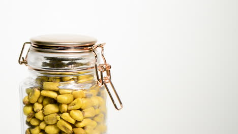 Toasted-golden-corn-kernels-in-glass-mason-jar,-rotating-set-against-white-studio-background