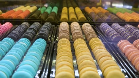Panning-shot-across-colourful-rows-of-macaroon-cookie-sweet-confectionery-in-store-window-display
