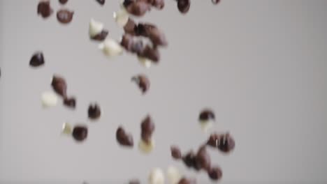 Milk,-white,-and-dark-chocolate-chips-raining-down-in-slow-motion-4k-with-gray-backdrop