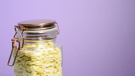 Detail-sliced-almonds-in-an-airtight-mason-jar-rotating-on-a-neon-lilac-background