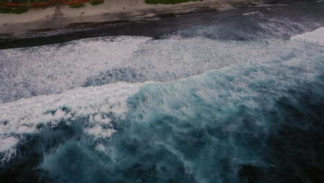 Aerial-birds-eye-view-of-dramatic-dark-moody-ocean-water-with-white-foaming-waves-breaking
