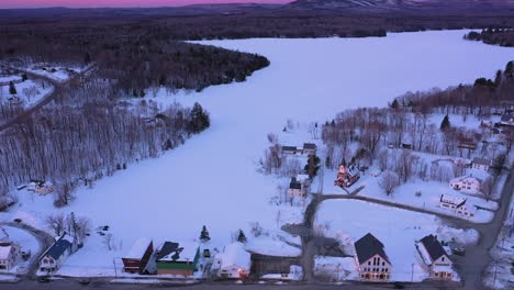 AERIAL-SLIDE-and-TILT-to-reveal-a-small-town-on-the-shore-of-a-frozen-lake-during-an-amazing-sunrise