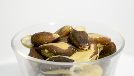 Transparent-glass-bowl-with-Brazil-nuts-rotating-on-a-white-background