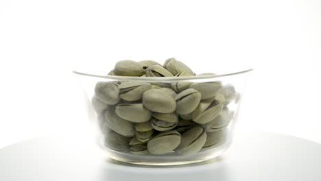 A-glass-bowl-of-pistachio-nuts-rotating-clockwise-on-a-white-background