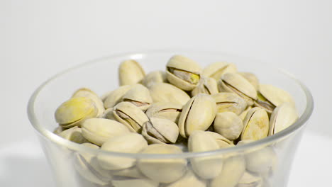 Transparent-bowl-with-pistachio-nuts-rotating-on-a-white-background