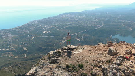 Static-aerial-shot-of-male-tourist-from-behind-enjoying-the-view-of-Marbella-from-top-of-La-Concha-in-Spain