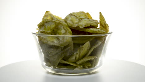 Glass-bowl-with-banana-chips-rotating-on-a-white-background