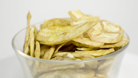 Detail-of-banana-chips-in-a-glass-jar-rotating-on-a-white-background