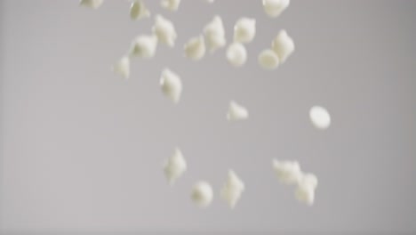 White-chocolate-chips-raining-down-in-slow-motion-4k-with-gray-backdrop
