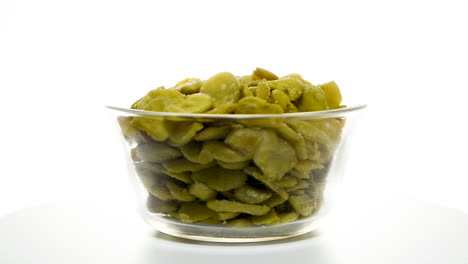 Rotating-glass-bowl-isolated-on-white-background-filled-with-toasted-fava-beans