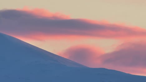 Luz-De-Puesta-De-Sol-Y-Nubes-Rodantes-Sobre-Picos-De-Montañas-Cubiertas-De-Nieve-Del-Norte-De-Noruega-En-Invierno,-Lapso-De-Tiempo,-Bellas-Imágenes-De-La-Naturaleza,-Larga-Duración