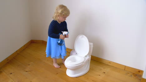 Child-spraying-liquid-in-a-potty-toilet