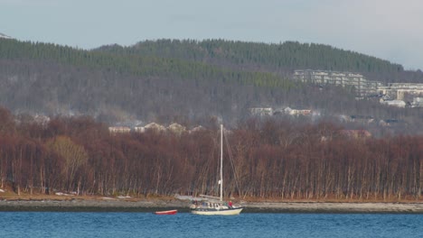 Kleines-Boot,-Das-Entlang-Des-Fjords-In-Nordnorwegen-Segelt,-Teleaufnahme-In-Zeitlupe-Mit-60-Bildern-Pro-Sekunde