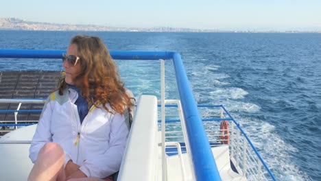 Beautiful-view-of-the-Mediterranean-Sea-with-young-woman-on-a-boat-ride-leaving-Naples,-Italy