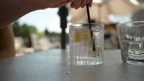 Hand-mixes-glass-of-water-with-lemon-and-lime-in-it-on-a-patio-table