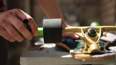 Man's-hands-as-he-uses-tool-to-unscrew-longboard-wheel