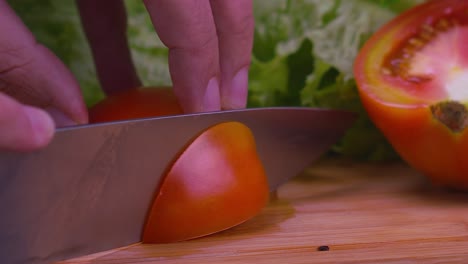 A-professional-chef-slices-a-juicy-red-tomato,-slow-motion-close-up