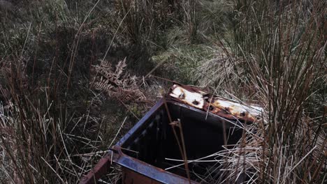 Piece-of-rusty-metal-lying-in-the-grass,-illegal-dump-of-garbage