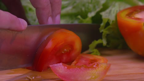 Nahaufnahme-Der-Hände-Eines-Küchenchefs-Mit-Einem-Messer,-Um-Eine-Saftige-Tomate-In-Scheiben-Zu-Schneiden
