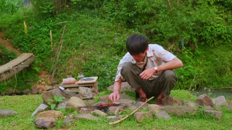 Asian-young-man-eating-on-rural-green-ground-making-rustic-barbecue