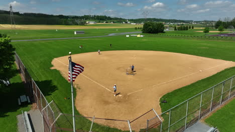 American-flag-waves-in-front-of-teens-playing-baseball