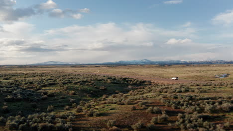 Aerial-tracking-shot-of-car-driving-through-large-open-Idaho-landscape
