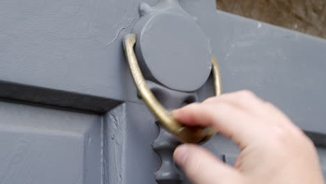 Close-up-of-a-man-using-a-door-knocker-to-knock-on-a-door