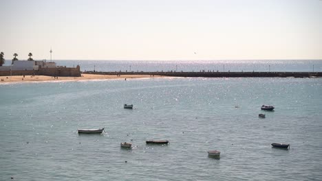 Paisaje-Mágico-Con-Océano-Brillante-Y-Pequeños-Barcos-De-Pesca-En-Cádiz,-España