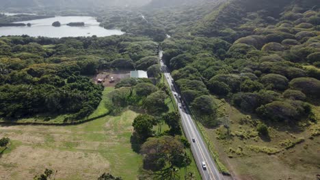 4K-clockwise-cinematic-drone-shot-of-cars-driving-down-a-road-with-a-pond-in-the-background-near-the-coast-of-Oahu's-North-Shore