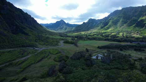 Aerial-reveal-of-lush-green-Hawaiian-mountains-and-valley-into-tropical-beach-and-ocean
