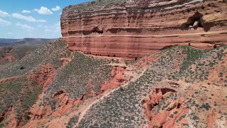 Hiker-climing-to-a-mistic-red-mountain-in-a-red-canyon-dessert-in-Teruel,-Spain