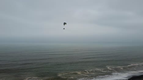 Drone-video-of-a-powered-paraglider-or-trike-flying-over-the-ocean-waves-in-Lima,-Peru