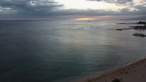 4K-Kinokran,-Der-Während-Des-Sonnenuntergangs-In-Oahu-Hinter-Einer-Palme-Am-Strand-Von-Waikiki-Aufgenommen-Wurde