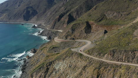 Car-driving-on-winding-coastal-highway-with-scenic-view-of-Pacific-ocean,-California