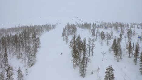 Drone-flyover-foggy-Levi-south-park-ski-resort,-Finland-hills