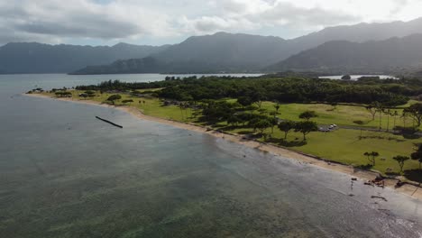 Toma-De-Drones-Cinematográficos-De-4k-En-El-Sentido-De-Las-Agujas-Del-Reloj-De-Olas-Rompiendo-Silenciosamente-En-El-Parque-De-La-Playa-De-Kualoa-En-Oahu
